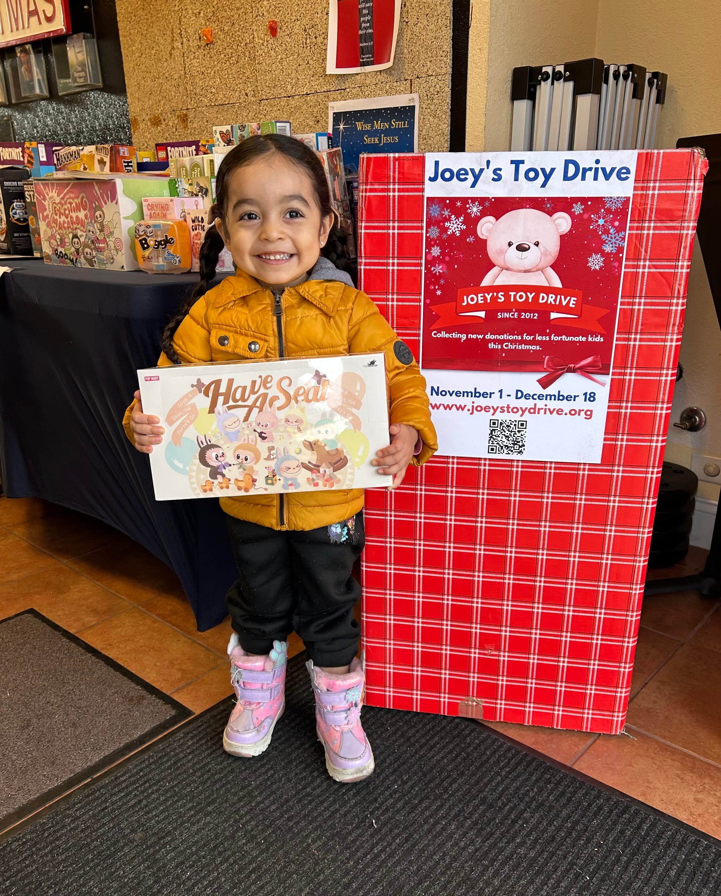 A young donor holding a book beside a donation box