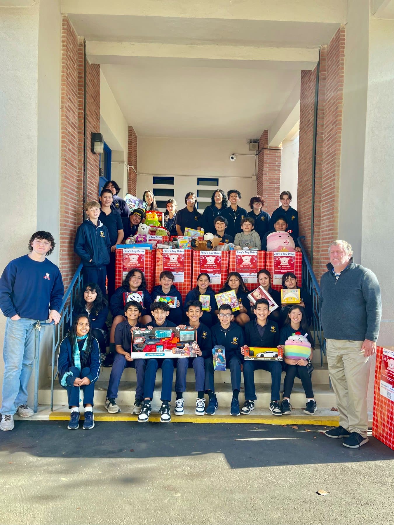 A group of student volunteers holding a Joey's Toy Drive sign at their school's collection drive